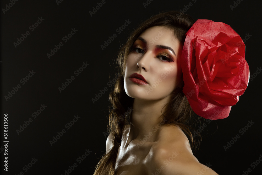 Vintage portrait of fashion glamour girl with red flower in her hair, over black. Studio shot. Spanish Carmen style