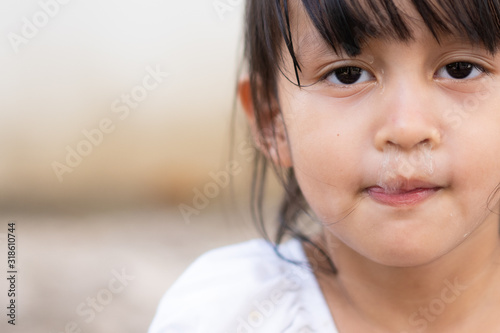 Close up face of asian little girl with snot runny nose from common cold and allergy symptom, concept of health care in child and impact of health from viral and air pollution.
