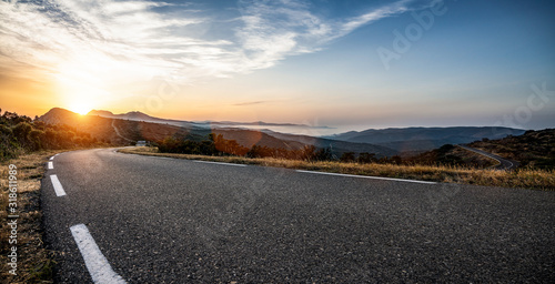 Empty long mountain road to the horizon on a sunny summer day at bright sunset Fototapeta