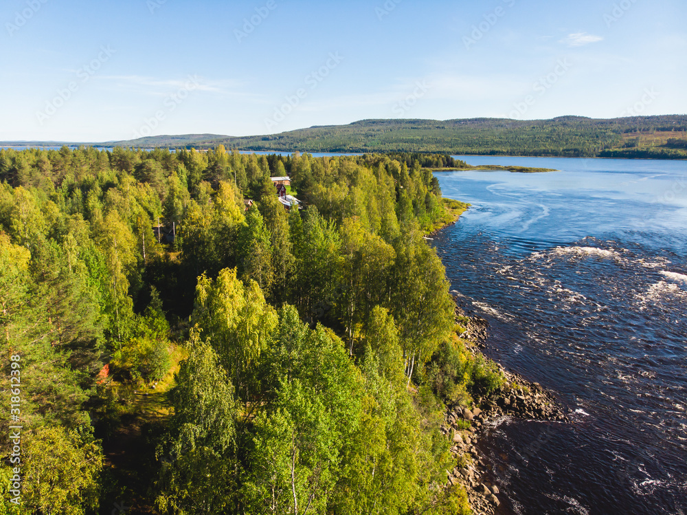 Obraz premium View of Kalix river, Kalixalven, Overkalix locality and the seat in Norrbotten county, Sweden, with forest in sunny summer day, aerial drone view