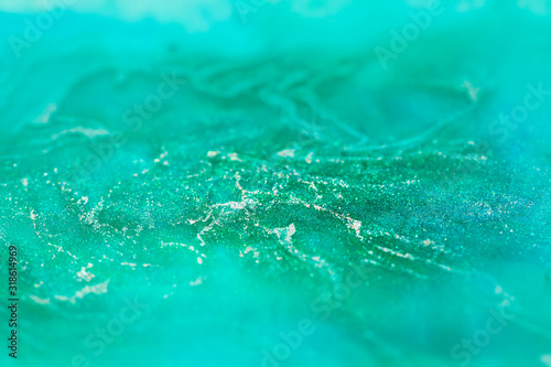 macro shot of alcohol ink with glitter dissolved in water, abstract turquoise background