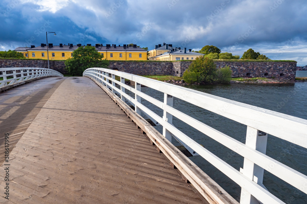 Helsinki. Finland. Pedestrian bridge with white wooden railings in the fortress of Sveaborg. The ancient fortress of Suomenlinna. Sights Of Helsinki. Fortress on the background of gray water.
