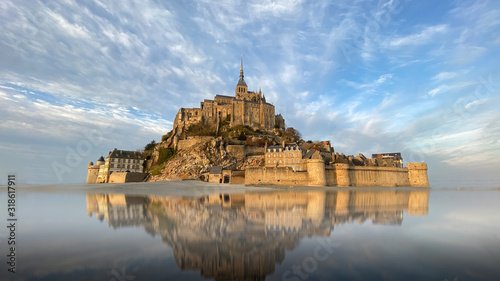 Fotografie, Obraz Beautiful Mont Saint Michel with water reflection and clouds on blue sky, France