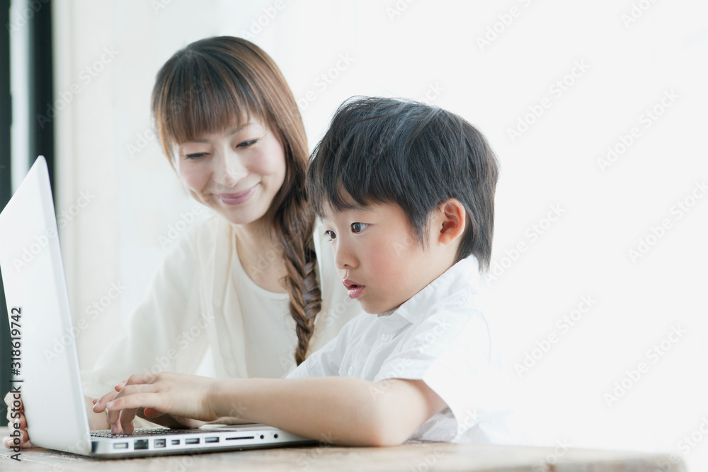 Mother assisting son using laptop at table Mother assisting son using laptop at table