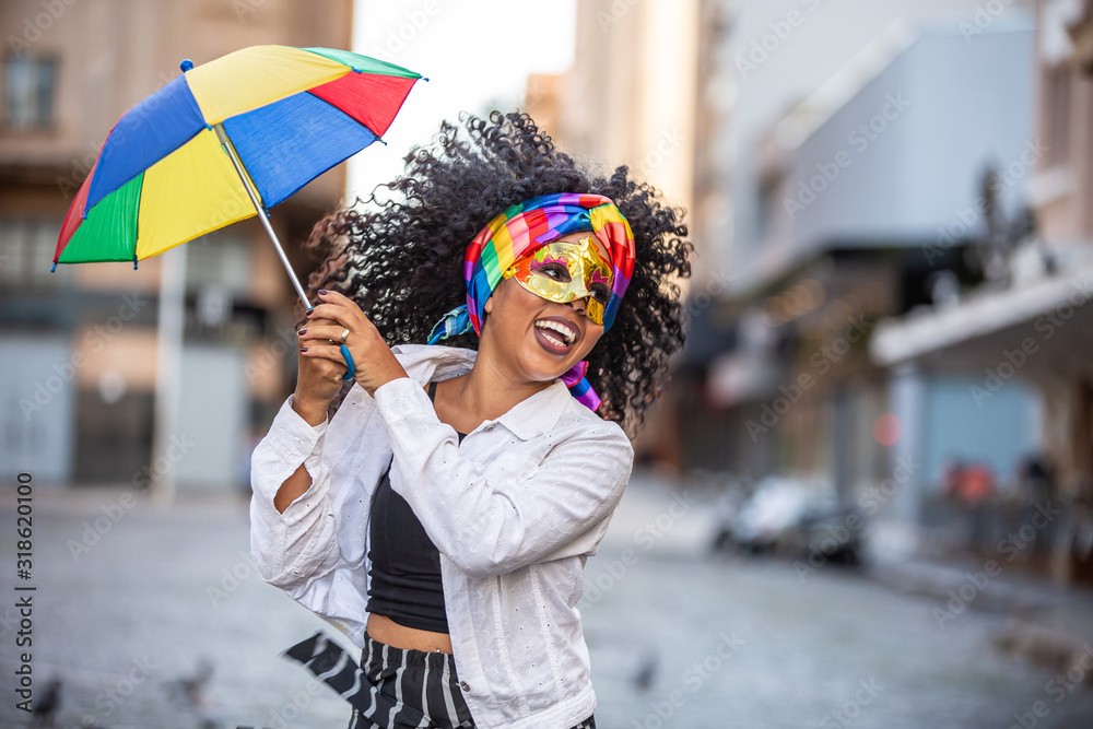 Young curly hair woman celebrating the Brazilian carnival party with Frevo umbrella on street. - obrazy, fototapety, plakaty 