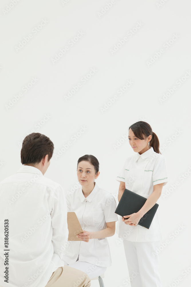 Studio shot of two nurses talking to patient Studio shot of two nurses talking to patient
