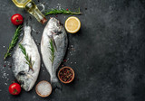 Fresh dorado fish with spices and ingredients tomato, razmorin, sunflower oil, lemon for cooking on a stone background with copy space for your text