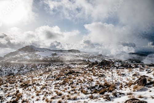 impressive background of a snowy mountain at sunset with dense clouds with lots of color © Juan