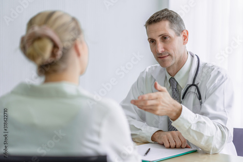 Senior doctor discussing to illness with young female patient at hospital office.Medicine and health care concept