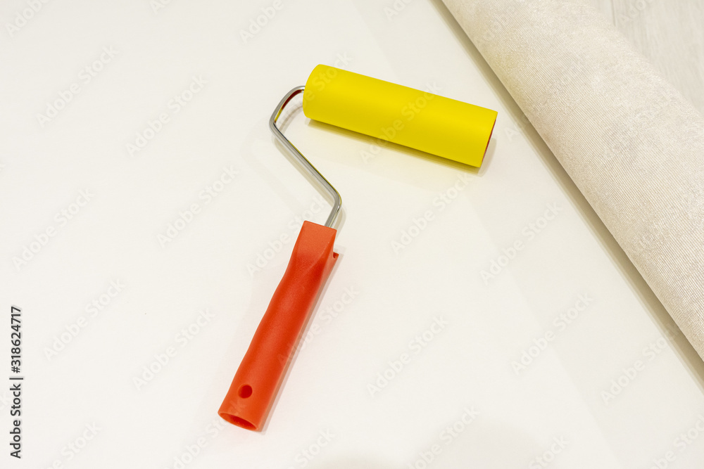 The concept of wallpapering. at home, a roller for smoothing on the back of the Wallpaper The concept of wallpapering. at home, a roller for smoothing on the back of the Wallpaper
