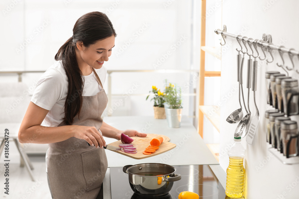 Young woman cooking tasty vegetable soup in kitchen Young woman cooking tasty vegetable soup in kitchen