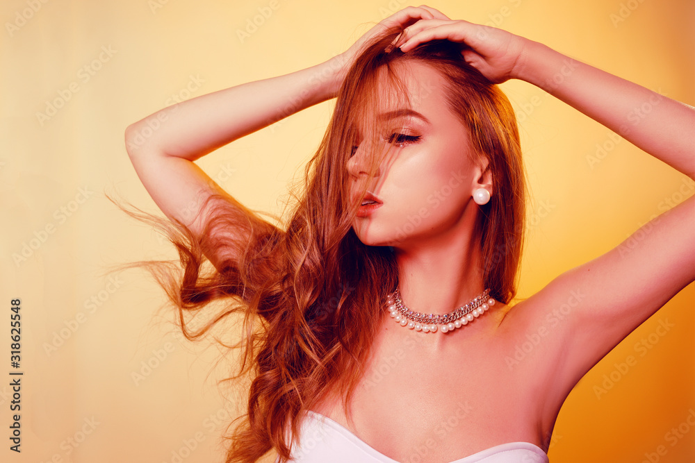 Obraz premium Fashion photo of a beautiful girl with creative make-up with pearls. Girl in orange color with long hair posing beautifully. Dance.