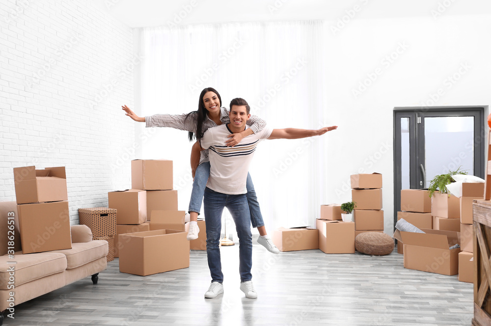Happy couple having fun in room with cardboard boxes on moving day Happy couple having fun in room with cardboard boxes on moving day