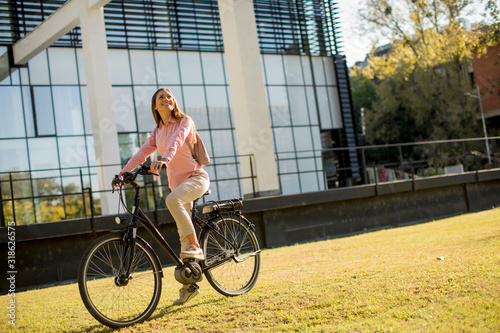 Fototapeta Naklejka Na Ścianę i Meble -  Young woman riding e bike in urban enviroment