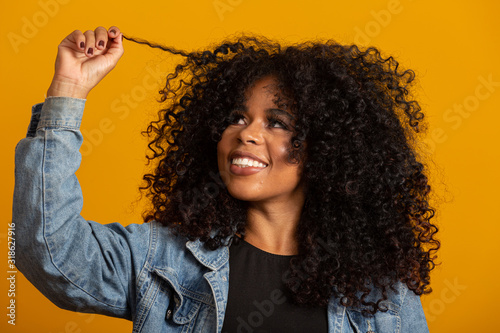 Canvas-taulu Young afro-american woman with curly hair looking at camera and smiling