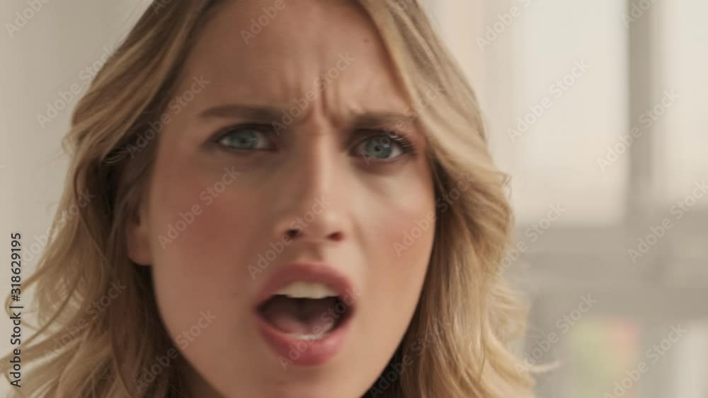 Close up view of confused displeased woman is arguing while looking to the camera in the white studio Close up view of confused displeased woman is arguing while looking to the camera in the white studio