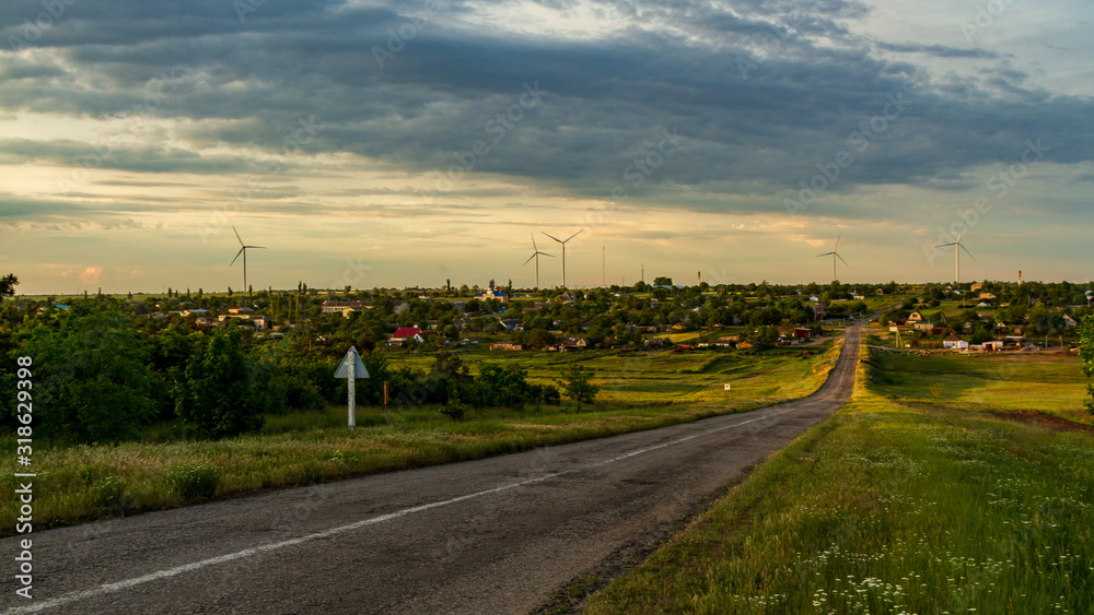 Naklejka premium road to the village with electric turbines, a church with blue domes, flock of sheep