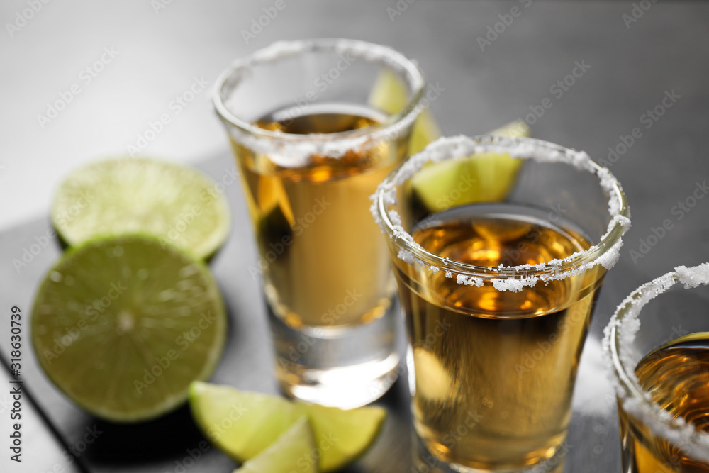 Mexican Tequila shots with salt and lime slices on grey table, closeup Mexican Tequila shots with salt and lime slices on grey table, closeup