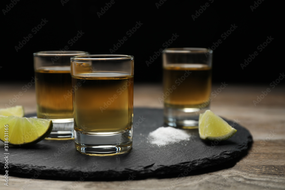 Mexican Tequila shots, lime slices and salt on wooden table Mexican Tequila shots, lime slices and salt on wooden table