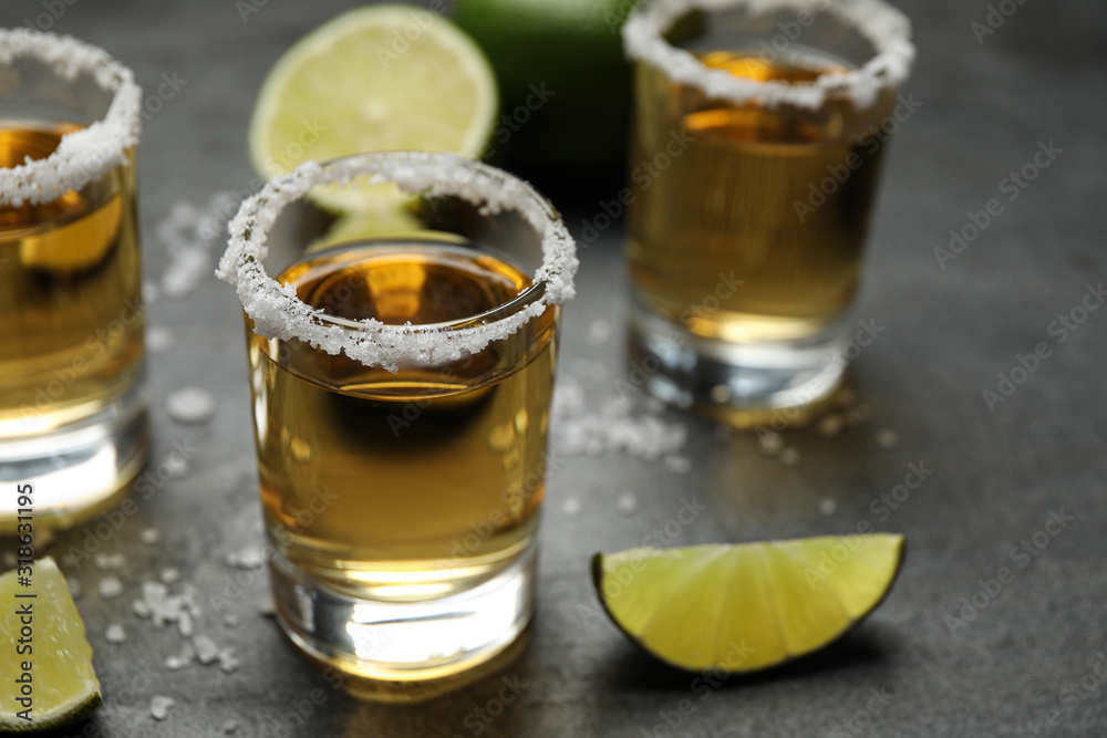 Mexican Tequila shots, lime slices and salt on grey table Mexican Tequila shots, lime slices and salt on grey table