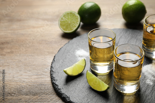 Mexican Tequila shots, lime slices and salt on wooden table