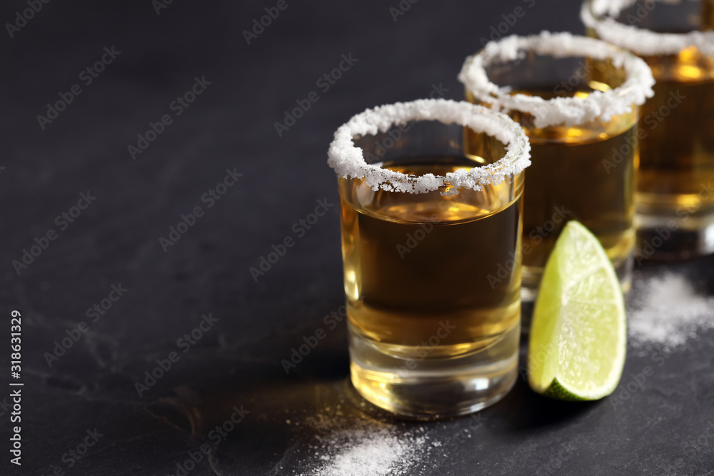 Mexican Tequila shots, lime slices and salt on grey table. Space for text Mexican Tequila shots, lime slices and salt on grey table. Space for text