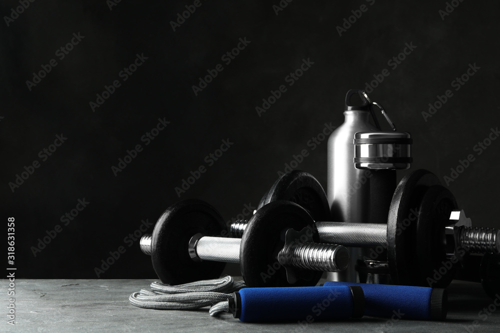 Gym equipment and accessories on stone floor against dark background Gym equipment and accessories on stone floor against dark background