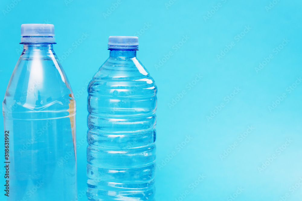 Two different plastic bottles with a sparkle of water on a blue background. Copyspace, place for text Two different plastic bottles with a sparkle of water on a blue background. Copyspace, place for text