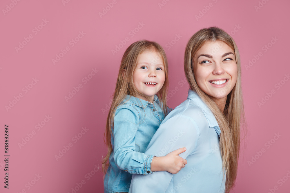 adorable sweet young mother with cute little daugher on pink bacground