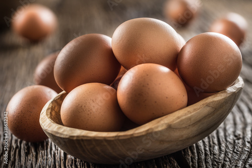 Fresh raw eggs in wooden bowl on rustic wooden table