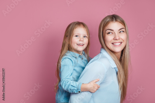 adorable sweet young mother with cute little daugher on pink bacground