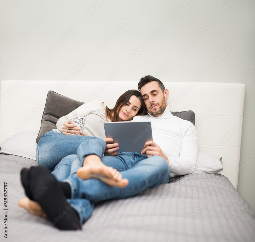Couple watching a movie on their tablet while on the bed Couple watching a movie on their tablet while on the bed