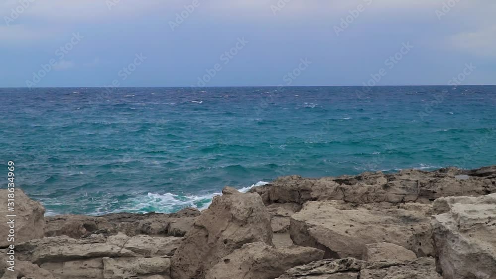 Storm at sea. Big waves break on the rocky shore, white foam on the water. Slow motion