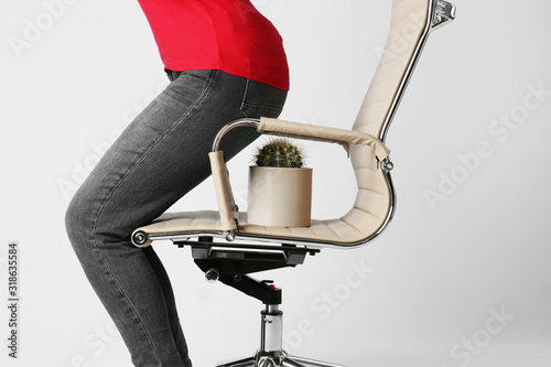 Woman sitting down on chair with cactus against white background, closeup. Hemorrhoids concept