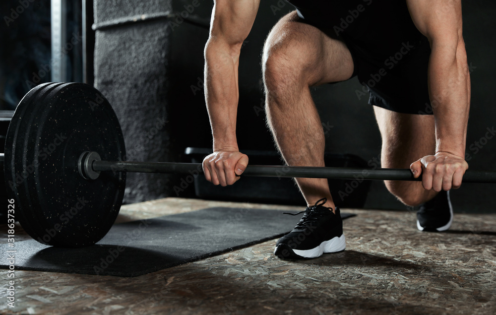 Fototapeta Man lifting barbell in modern gym, closeup
