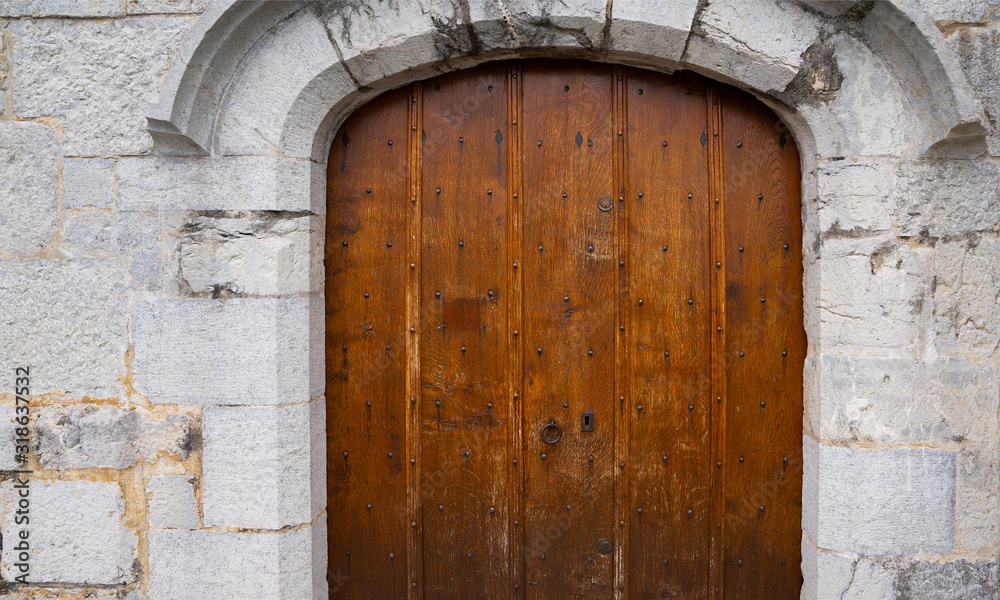 Medieval castle gate. Ancient wooden door in old stone castle wall. Locked wooden door with metal forging. Medieval castle gate. Ancient wooden door in old stone castle wall. Locked wooden door with metal forging.