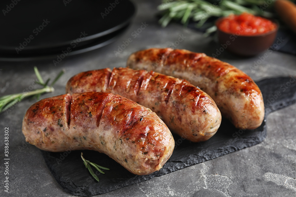 Tasty grilled sausages on grey table, closeup Tasty grilled sausages on grey table, closeup