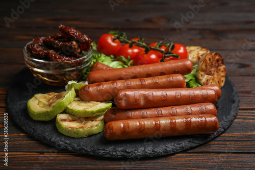 Delicious grilled sausages served on wooden table
