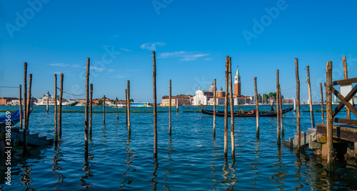 Venice Canals and gondolas around Saint Marco square on a bright sunny day. Old pier. Architecture and landmarks of Venice. Vacation and holidays in Italy and Europe concept.