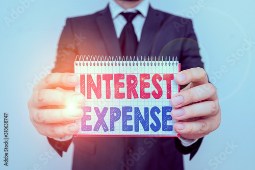 Writing note showing Interest Expense. Business concept for cost of debt that has occurred during a period of time Male human wear formal work suit with office look hold book photo