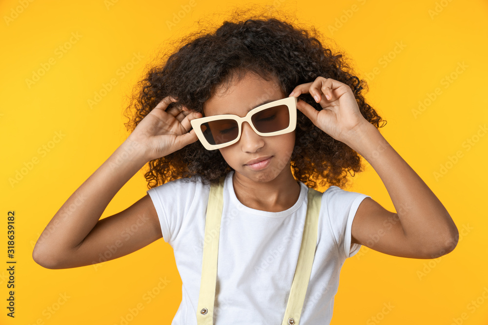 Young beautiful curly girl in sunglasses looking bored over isolated yellow background Young beautiful curly girl in sunglasses looking bored over isolated yellow background