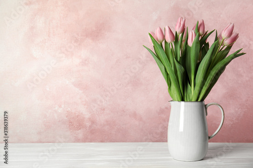 Beautiful pink spring tulips in vase on white wooden table. Space for text