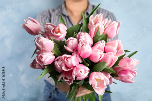 Woman with beautiful pink spring tulips on light blue background  closeup