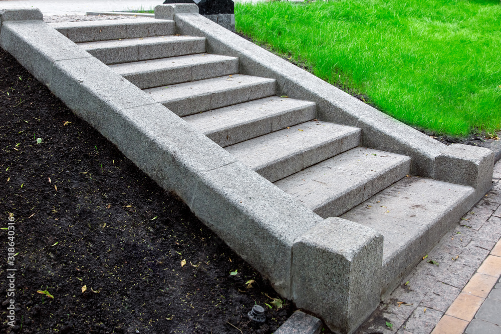 Φωτογραφία a granite staircase of stone blocks climbing up a slope with soil and green grass in the park nobody, close up side view