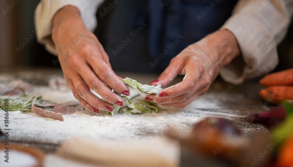 Fresh homemade pasta with pasta ingredients on the dark wooden table top view. Female making homemade pasta with flour and eggs over old wooden table.