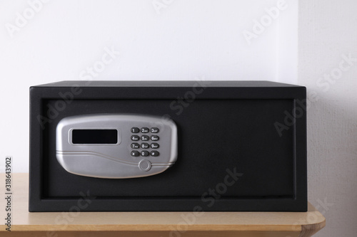 Black steel safe with electronic lock on wooden table