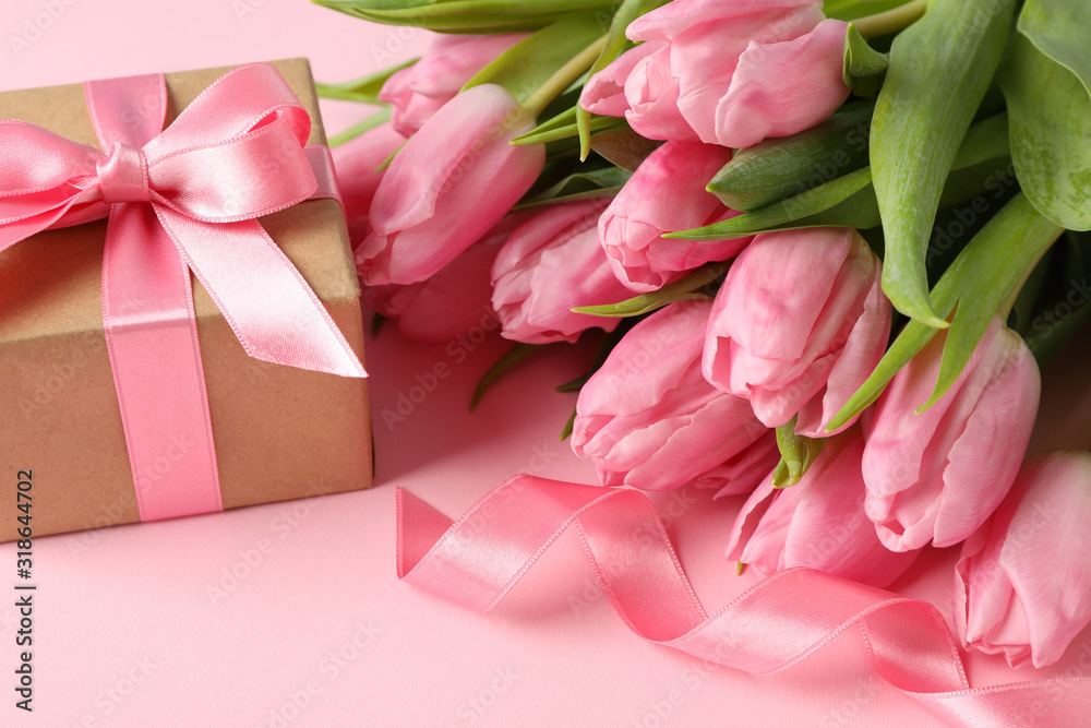 Fototapeta premium Bouquet of pink tulips and gift box on pink background, close up