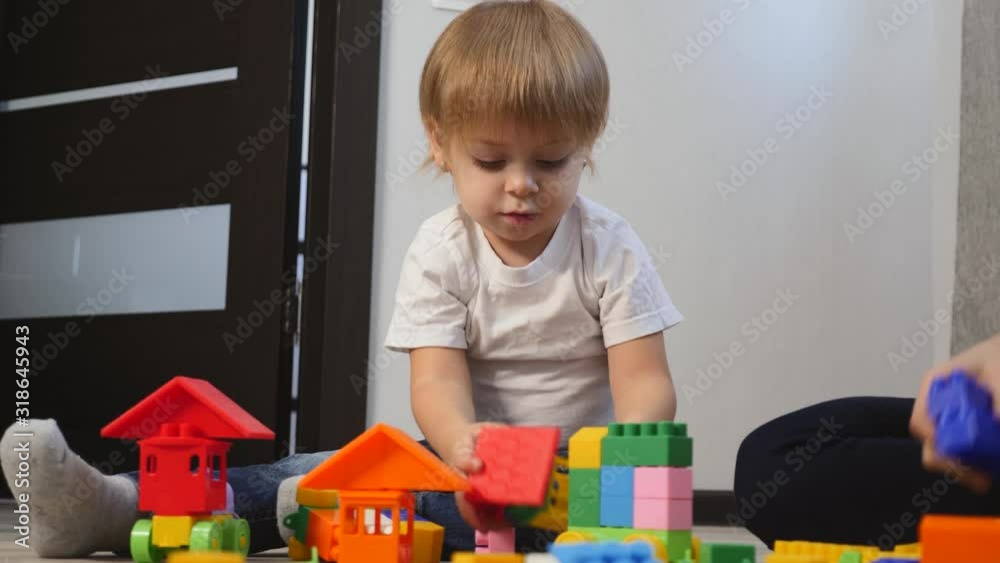 Blond little children play with bright cubes on the floor at home. Blond little children play with bright cubes on the floor at home.