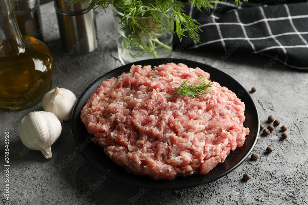 Spices and plate with minced meat on grey background, close up Spices and plate with minced meat on grey background, close up