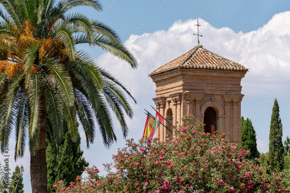 Alhambra Convent of San Francisco of Granada tower with a colorful garden and a palm tree, spain